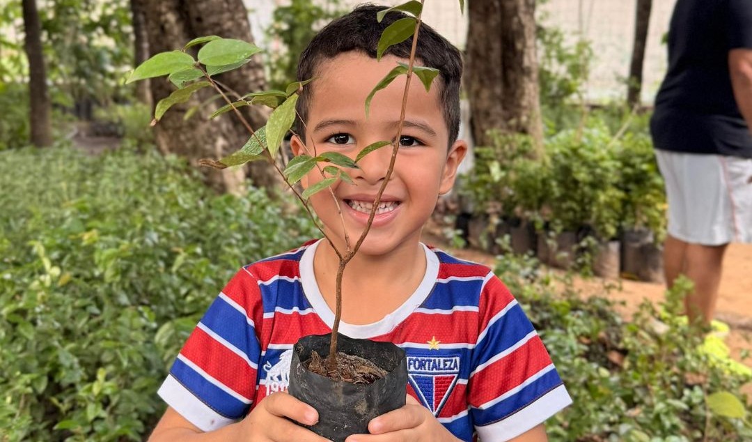 criança com camisa do Fortaleza posa com a foto de uma muda na mão